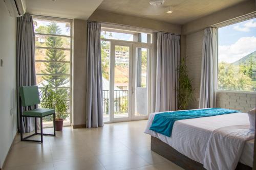um quarto com uma cama e janelas grandes em Kurumbunkz em Kandy