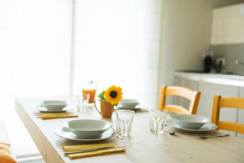 a table with plates and glasses and a sunflower on it at Quader nidi nel verde in Bienno