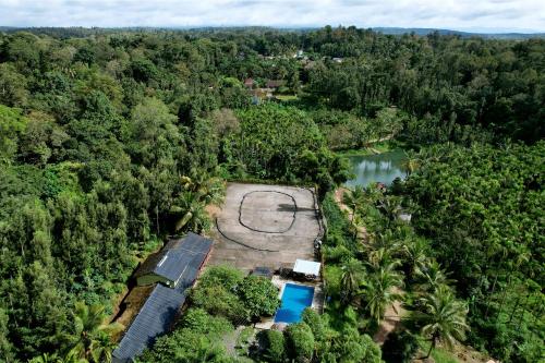an aerial view of a resort with a pool in the forest at Leisure Homestay - Pool, Boating, Zipline, Home Food, Estate in Chikmagalūr