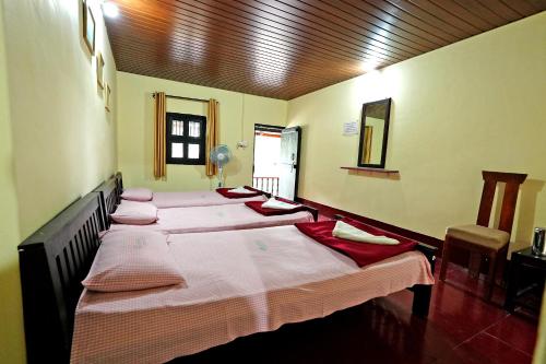 a group of three beds in a room at Leisure Homestay - Pool, Boating, Zipline, Home Food, Estate in Chikmagalūr