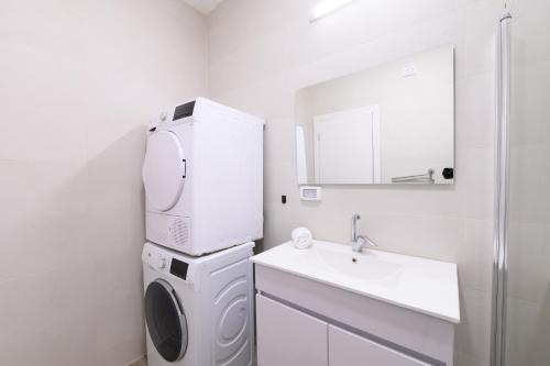 ein weißes Badezimmer mit einer Waschmaschine und einem Waschbecken in der Unterkunft דירת נופש התבור Hatvor condo in Shadmot Devora