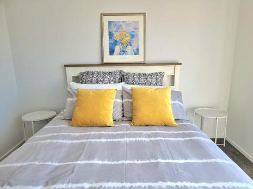 1 dormitorio con 1 cama con almohadas amarillas y grises en Addington townhouse with carpark 8mins walk to Hagley park south en Christchurch