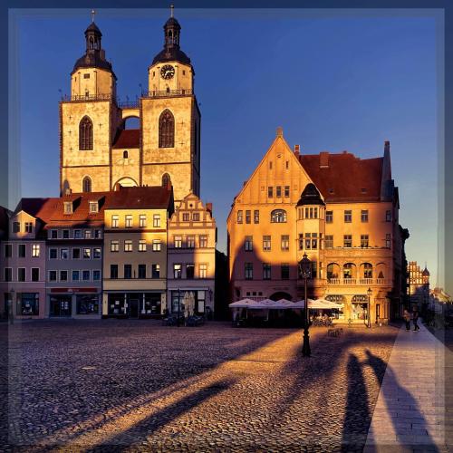a group of buildings with a shadow of a person at ALTE SCHULE WITTENBERG, 3 Ferienwohnungen für bis zu 12 Personen, an der Elbe, mit Garten in Lutherstadt Wittenberg