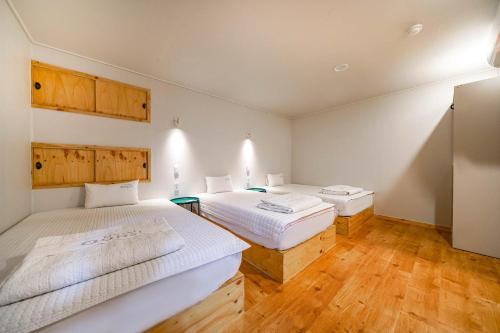 two beds in a room with wooden floors at Oops Hotel in Busan