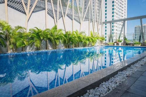 a swimming pool with palm trees and buildings at The Art Nest Hotel Nha Trang in Nha Trang