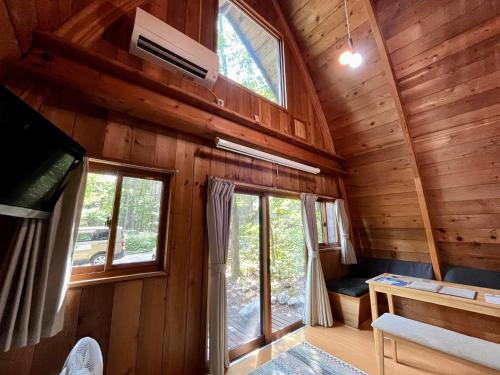 a room with wooden walls and windows in a cabin at Yukiita Lodge in Hakuba