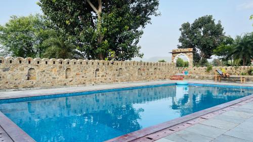 una piscina accanto a un muro di mattoni di Kutani Bagh - Best Hotel in Sariska National Park a Tehla