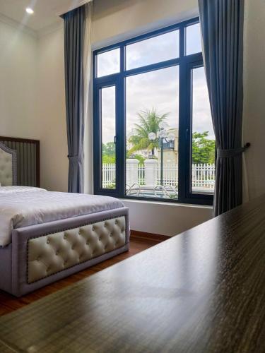 a bedroom with a bed and a large window at Phượng Hoàng villa - bể bơi, phòng karaoke, sân Pickleball, xe địa hình, xe đạp đôi in Ha Long