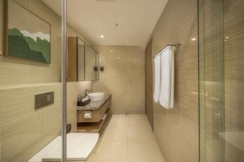 a bathroom with a sink and a glass shower at Pan Pacific Serviced Suites Nairobi in Nairobi