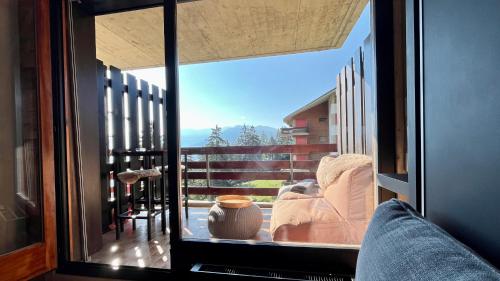a room with a large window with a view of a balcony at Les Cerfs - Appartement & Studio - ANZERE in Anzère
