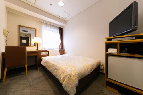 a room with a bed and a desk and a television at Hotel Ohedo in Tokyo