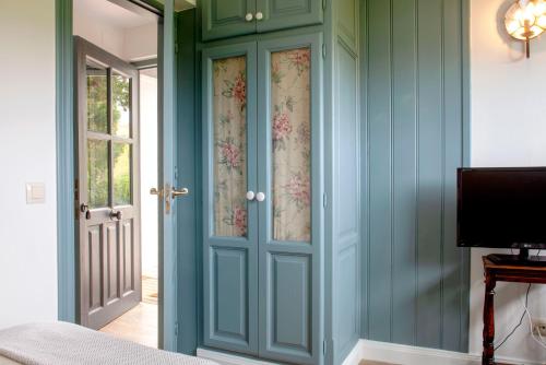 a bedroom with green walls and a door with floral curtains at Wishome-La casa más especial de Oyambre, Comillas in San Vicente de la Barquera