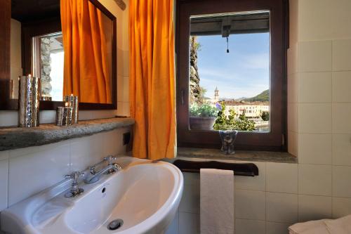 baño con lavabo y ventana con cortinas de color naranja en La Torre Di Porlezza, en Porlezza