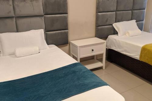 a hotel room with two beds and a night stand at Holiday Haven in Gaborone