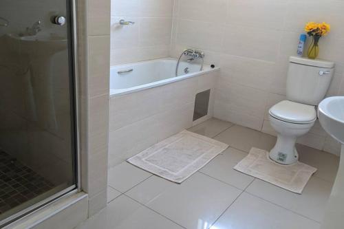 a bathroom with a toilet and a tub and a sink at Holiday Haven in Gaborone