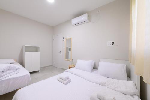 Duas camas num quarto branco com lençóis brancos em דירת נופש מרחבים Merhavim Villa em Shadmot Devora