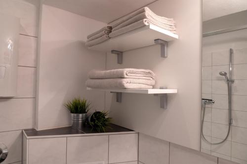 een badkamer met witte muren, een douche en handdoeken bij Ferienwohnung Bonnie und Kleid in Saarburg