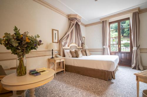 Un dormitorio con una cama y una mesa con un jarrón de flores en Gran Hotel Las Caldas by blau hotels en Las Caldas