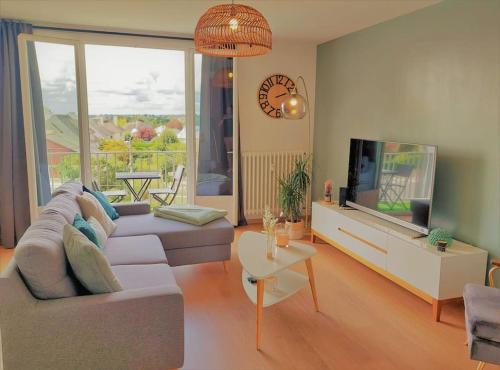 uma sala de estar com um sofá e uma televisão de ecrã plano em Le cocon vitréen ! em Vitré
