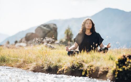 a woman is doing yoga by a river at Aparthotel Maso Corto in Maso Corto