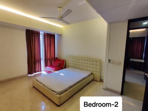 ein Schlafzimmer mit einem Bett und einem roten Stuhl in der Unterkunft Bay's Brookwood in Dhaka