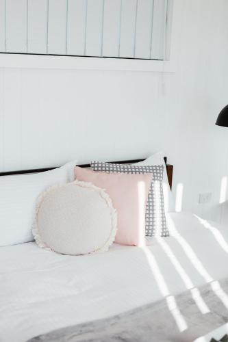 a white bed with a pink pillow on it at Rose Quartz - 1 Bed with Mountain Views - Kundalini Lodge in Grattai