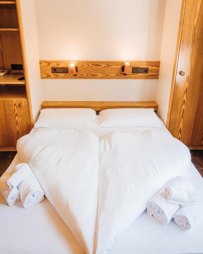 a bedroom with two beds with white sheets and towels at Aparthotel Maso Corto in Maso Corto