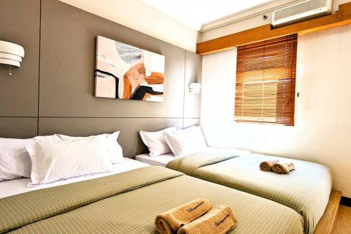 two beds sitting next to each other in a room at Cottonwood Japandi Apartment at Majesty 509 in Bandung