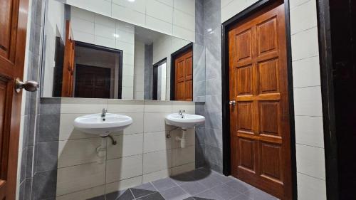 baño con 2 lavabos y puerta de madera en Rumah Amaan, en Kuah