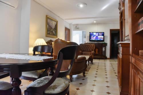 een woonkamer met een tafel en stoelen en een televisie bij Apartamento Santa cruz in Sevilla