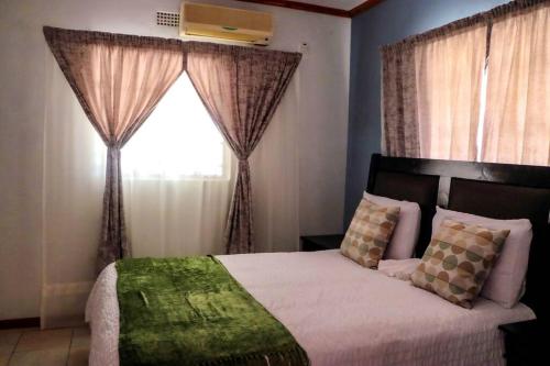 um quarto com uma cama e uma janela com cortinas em Yaxida's Warmth em Kasane