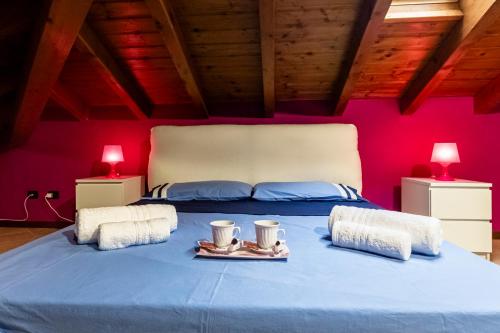 a bedroom with a blue bed with two cups and towels at Leonardo Academy in 5' - Parcheggio Gratis - laghi & Wi-FI in Sesto Calende