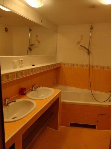 a bathroom with two sinks and a shower and a tub at Apartmán blízko centra Levice in Levice