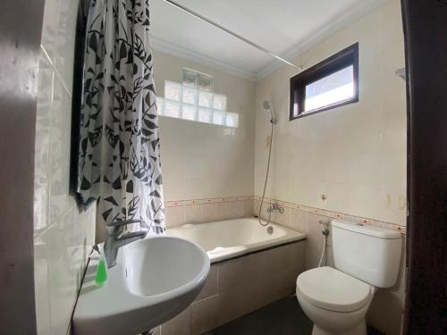 uma casa de banho com um WC, um lavatório e uma banheira em Dedy Beach Inn em Kuta