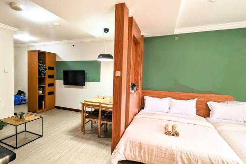 a bedroom with a large bed and a table at Cottonwood Midcentury Apartment at Majesty 811 in Bandung