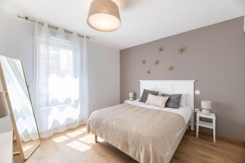 a white bedroom with a bed and a window at OVELIA Lyon - Les Jardins d'Hortense in Lyon