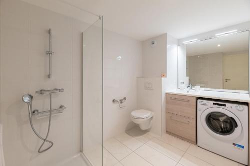 a bathroom with a shower and a washing machine at OVELIA Lyon - Les Jardins d'Hortense in Lyon