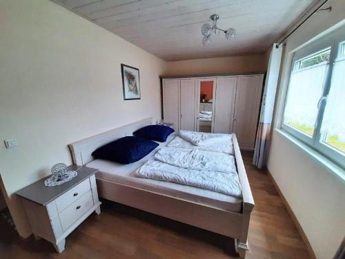 a bedroom with a bed with blue pillows and a window at Feriendorf Reichenbach - Dachspfad 7 in Nesselwang