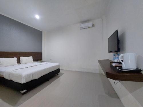 um quarto com uma cama e uma secretária com uma televisão em Grand Tawiri Hotel 