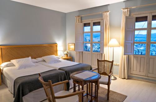 a bedroom with two beds and a table and chairs at Carmen de la Alcubilla del Caracol in Granada