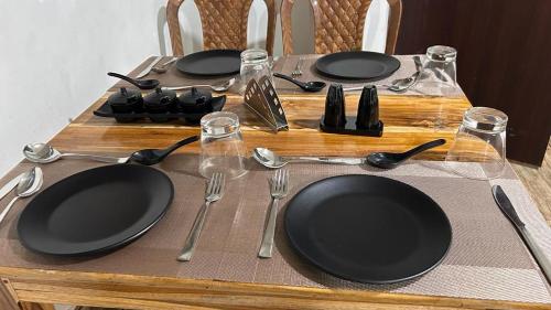 einen Tisch mit schwarzen Tellern und Küchenutensilien darauf in der Unterkunft Hotel Pearl Retreat by Nirvaan Hotels in Darjeeling