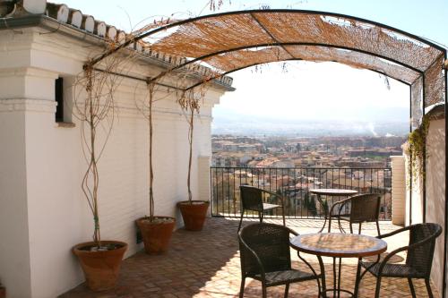 Un patio con mesas y sillas en un balcón. en Carmen de la Alcubilla del Caracol, en Granada