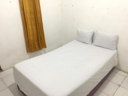 łóżko z białą pościelą i poduszkami w pokoju w obiekcie OYO Life 93009 Griya Nautika Sedati w mieście Sidoarjo
