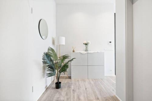 a white hallway with a potted plant and a mirror at Venture Vacations - 65 TV Netflix Free Parking King Bed Brand New in Reykjavík