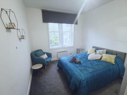 um quarto com uma cama azul e uma cadeira azul em Luxe & Stylish Centralised Watford Apt - Fast Wi-Fi & Free Parking Near Harry Potter Studios Tour em Watford