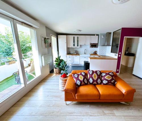 a living room with an orange couch and a kitchen at uta house la plaine in Saint-Denis