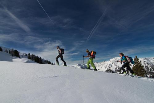 a group of three people walking up a snow covered slope at Brandstätterhof in Schladming