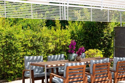 a wooden table with chairs and flowers on it at Mare Dei Suites Hotel Ionian Resort in Skafidia