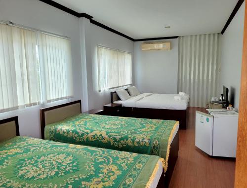 a hotel room with two beds and a television at Tara Spa Ratchaburi in Ban Bang Kra