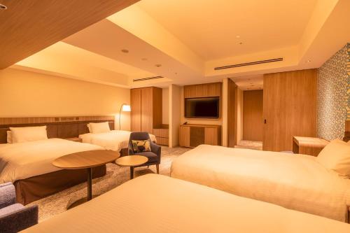 a hotel room with two beds and a television at Hotel Emion Sapporo in Sapporo